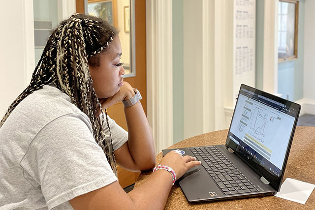 undergraduate student in white lab coat sets up a test on scientific equipment